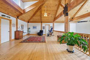 Living area featuring a high wooden beamed ceiling, light wood-type flooring, and ceiling fan