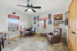 Office area featuring light stone finish floors and a ceiling fan