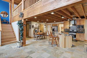 Kitchen featuring a kitchen breakfast bar, dark stone countertops, stone tile floors, and stainless steel appliances