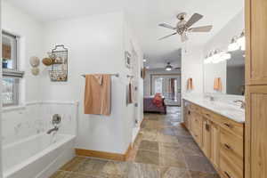 Bathroom with ensuite bath, double vanity, stone tile flooring, a garden tub, and ceiling fan