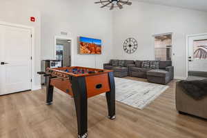 Rec room featuring light wood finished floors, vaulted ceiling, and a ceiling fan