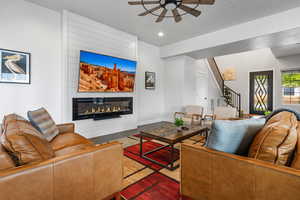 Living room with ceiling fan, a large fireplace, and recessed lighting