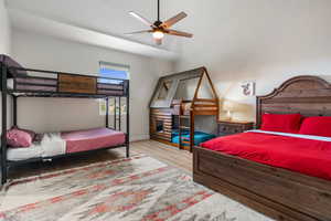 Bedroom with a ceiling fan, light wood finished floors, and vaulted ceiling