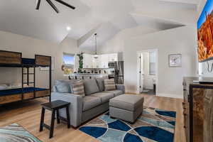 Living area featuring a high ceiling, light wood finished floors, and a ceiling fan
