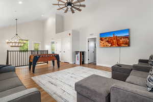Living area featuring light wood-type flooring, a chandelier, a ceiling fan, and lofted ceiling