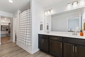 Owner’s ensuite bathroom featuring a double vanity with quartz countertops, cultured marble surround, and a separate toilet room.