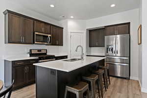 Kitchen featuring quartz countertops, ash gray cabinetry, stainless steel appliances, a gas range, double basin sink, and a pantry with ample storage.