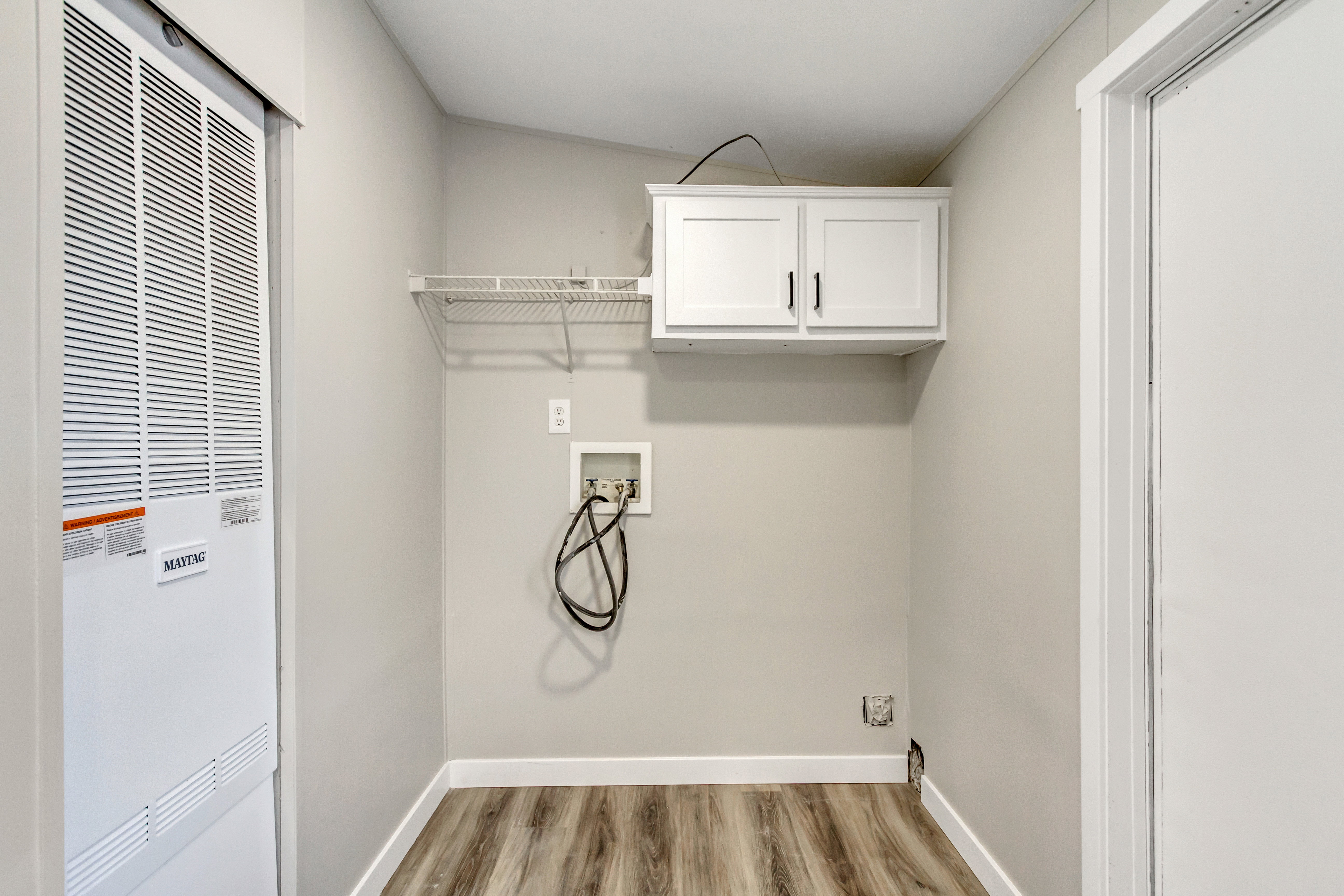 Laundry area featuring a heating unit, hookup for a washing machine, light wood-style flooring, and cabinet space