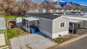 View of front of home featuring a mountain view, roof with shingles, a storage shed, and a residential view