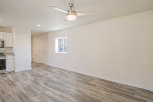 Kitchen with stainless steel appliances, a ceiling fan, light wood finished floors, recessed lighting, and white cabinetry