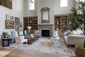 Living room with a high ceiling, a glass covered fireplace, wood-type flooring, and plenty of natural light
