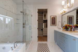 Full bathroom with a spacious closet, double vanity, a marble finish shower, and a bath