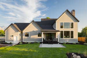 Rear view of property featuring a yard, a chimney, a patio area, and a mountain view