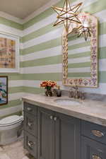 Half bath featuring vanity and wallpapered walls