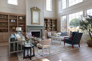Living area featuring a high ceiling, a tile fireplace, hardwood / wood-style floors, built in features, and wood walls