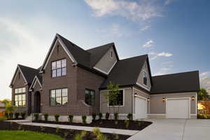 View of front of home with concrete driveway, a shingled roof, an attached garage, and brick siding