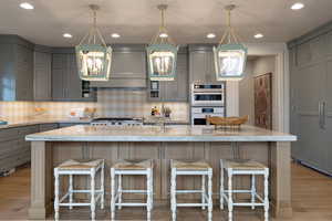 Kitchen with gray cabinets, light wood-style flooring, a kitchen bar, and light stone countertops