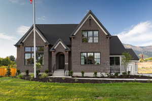 View of front of property featuring brick siding, a front yard, a mountain view, and roof with shingles