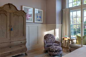 Bedroom featuring a decorative wall, wainscoting, and wood finished floors
