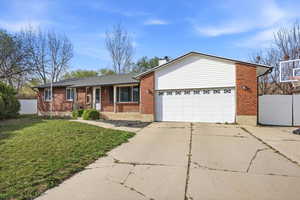 Ranch-style home with concrete driveway, covered porch, brick siding, and a chimney