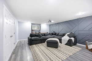 Cinema room with light wood-type flooring, an accent wall, and a decorative wall