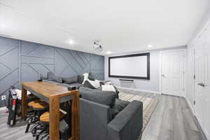 Home theater room with a decorative wall, light wood finished floors, and an accent wall