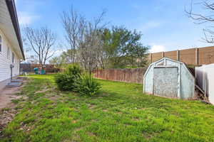 Fenced backyard featuring a storage unit