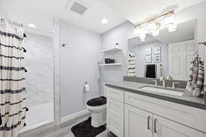 Full bath featuring vanity, a marble finish shower, and light wood finished floors
