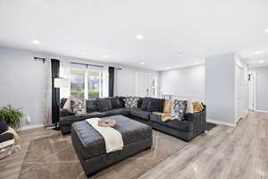 Living room with light wood finished floors and recessed lighting