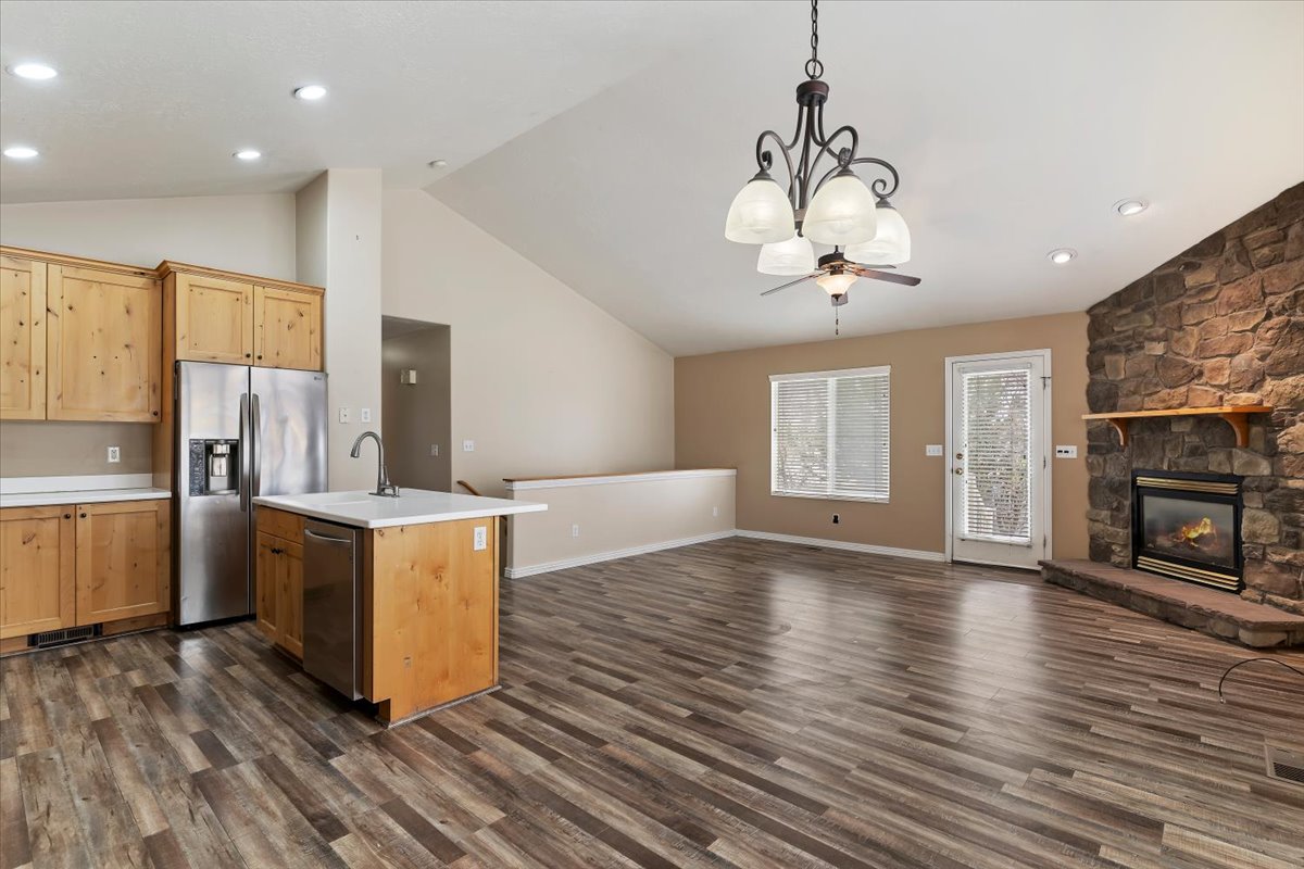 Kitchen with open floor plan, light countertops, stainless steel appliances, a fireplace, and a high ceiling