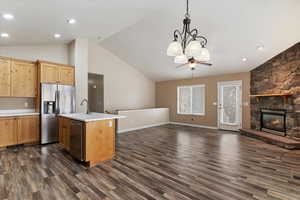 Kitchen with open floor plan, light countertops, stainless steel appliances, a fireplace, and a high ceiling