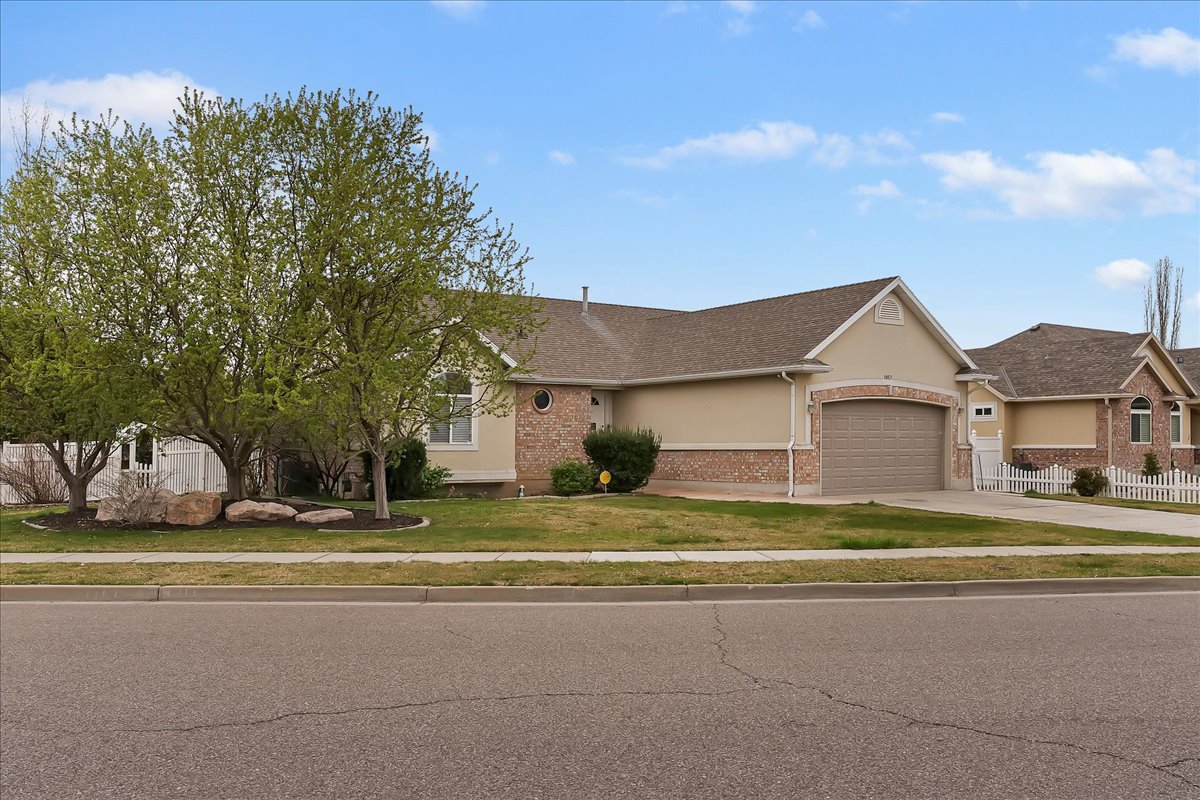View of front facade featuring a garage, concrete driveway, stucco siding, a shingled roof, and brick siding