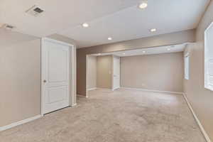 Below grade area featuring light colored carpet, recessed lighting, and a textured ceiling