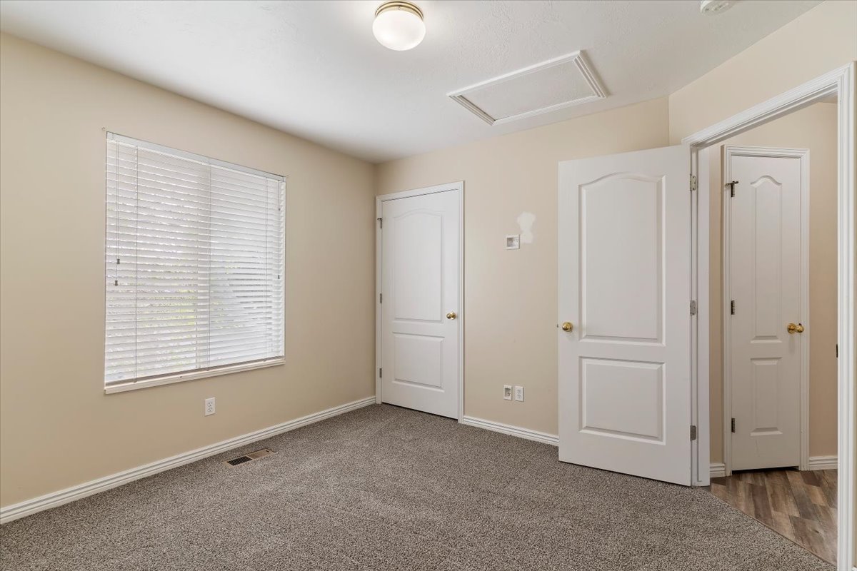 Unfurnished bedroom featuring attic access and dark carpet