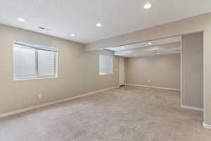 Empty room featuring light carpet, recessed lighting, and a textured ceiling