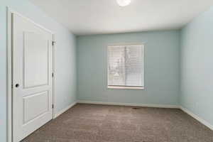 Unfurnished room featuring dark colored carpet and baseboards