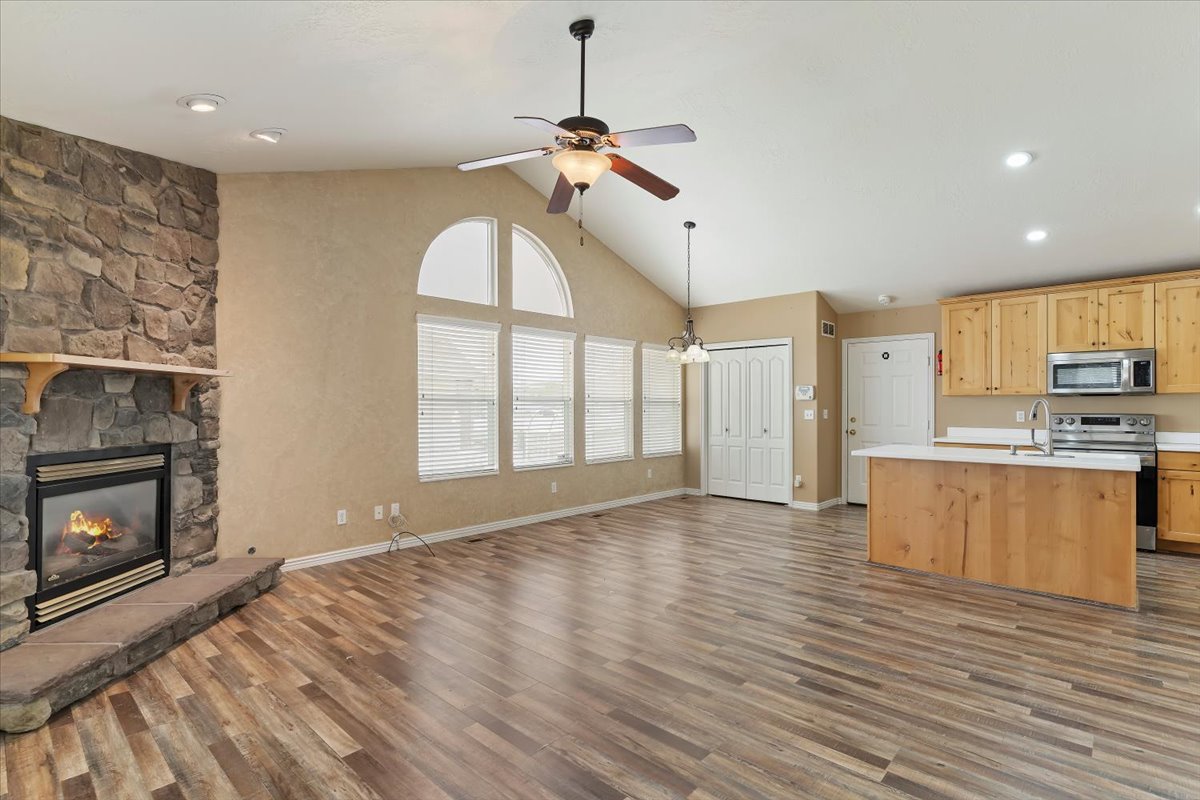 Kitchen featuring open floor plan, light countertops, light wood finish cabinetry, stainless steel appliances, and an island with sink