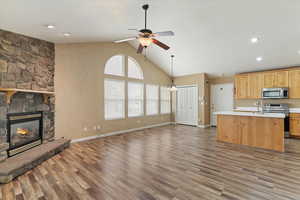 Kitchen featuring open floor plan, light countertops, light wood finish cabinetry, stainless steel appliances, and an island with sink