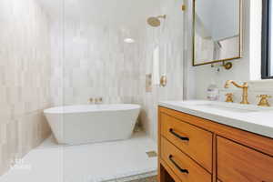 Bathroom with tile walls, vanity, and a freestanding bath