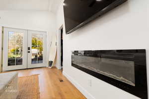 Doorway with french doors, wood finished floors, and vaulted ceiling