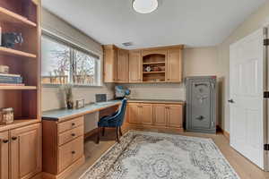 Office space featuring built in desk and light wood-style flooring