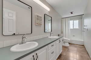 NEW QUARTZ COUNTER TOP COMING Bathroom with double vanity and shower / bathtub combination with curtain