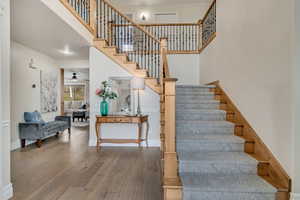 Staircase featuring hardwood / wood-style floors, a high ceiling, and ceiling fan