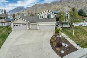 View of front facade with a mountain view, stucco siding, roof with shingles, roof mounted solar panels, and concrete driveway