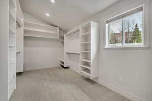 Primary Suite Walk in closet with light carpet and lofted ceiling