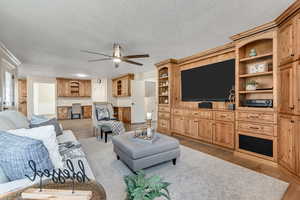 Living area with light wood-type flooring, ceiling fan, and a textured ceiling