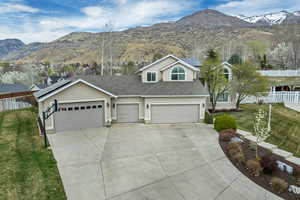View of front of home featuring a mountain view, roof mounted solar panels, concrete driveway, stucco siding, and a shingled roof