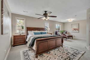 Primary Bedroom with light colored carpet, ceiling fan, and a textured ceiling