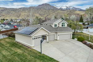 View of front of home with stucco siding, a mountain view, concrete driveway, roof with shingles, and roof mounted solar panels