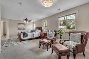 Primary Bedroom featuring light carpet, ceiling fan, and a textured ceiling